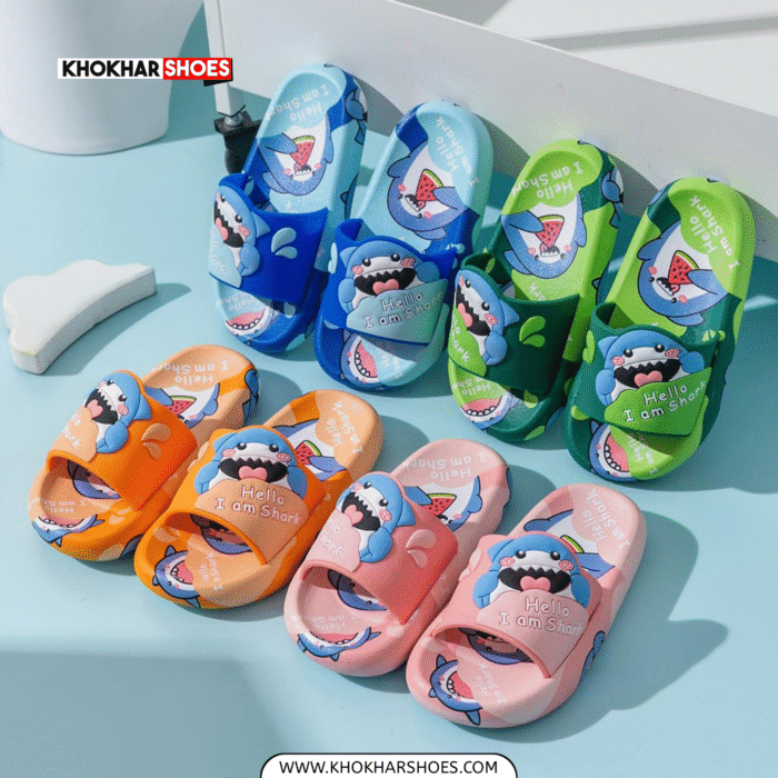 A pair of bright blue and light blue kids' slides with a cheerful 3D shark design on the straps, and small shark cartoon patterns on the footbeds. The slippers have thick, comfortable-looking soles.