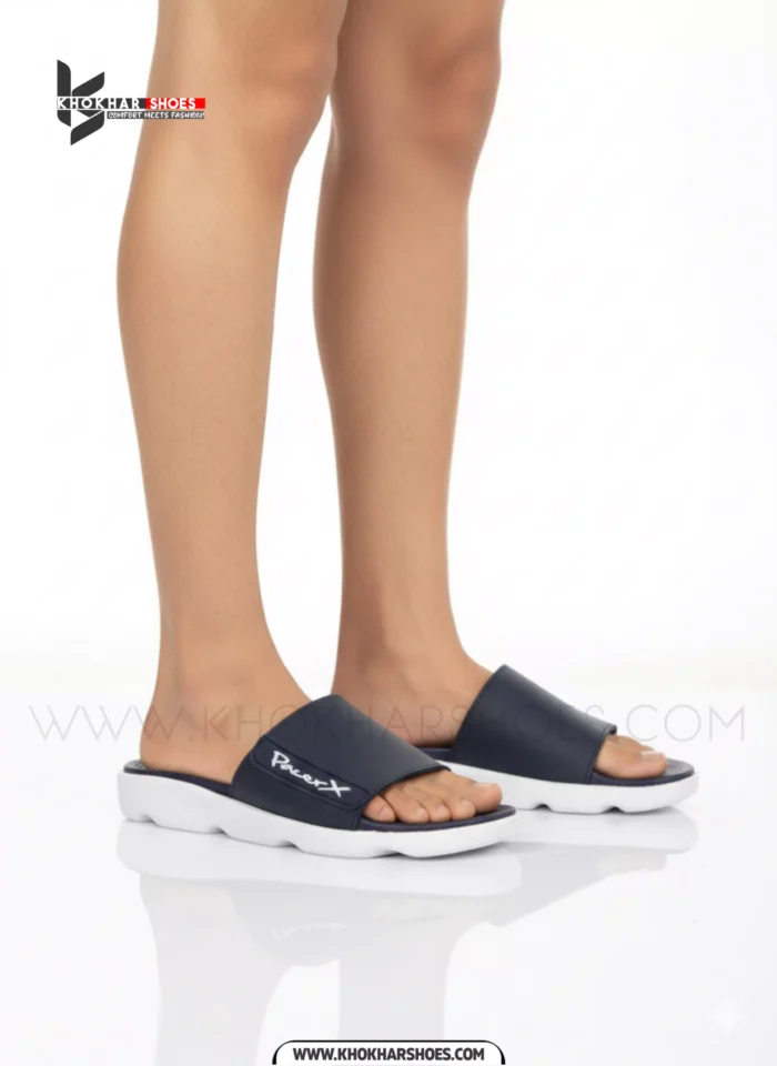 A man's feet in a pair of comfortable, navy blue and white, single-strap slides on a white background.