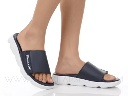 A man's feet in a pair of comfortable, navy blue and white, single-strap slides on a white background.