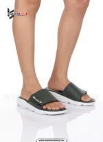 A man's feet in a pair of comfortable, navy blue and white, single-strap slides on a white background.