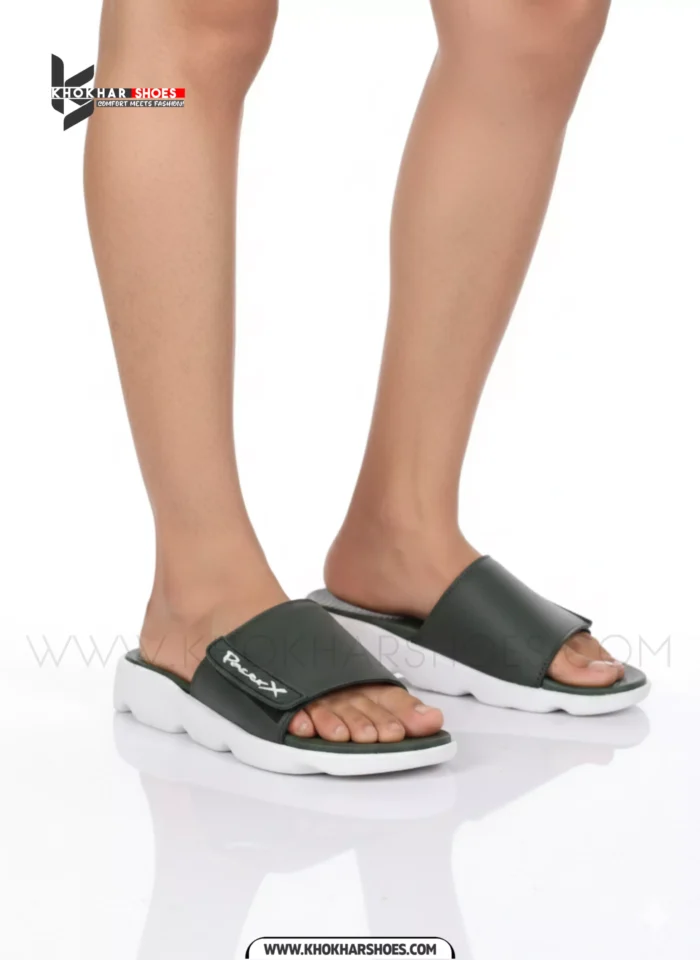 A man's feet in a pair of comfortable, navy blue and white, single-strap slides on a white background.