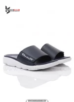 A man's feet in a pair of comfortable, navy blue and white, single-strap slides on a white background.