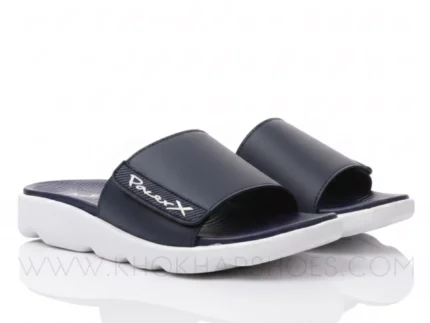 A man's feet in a pair of comfortable, navy blue and white, single-strap slides on a white background.