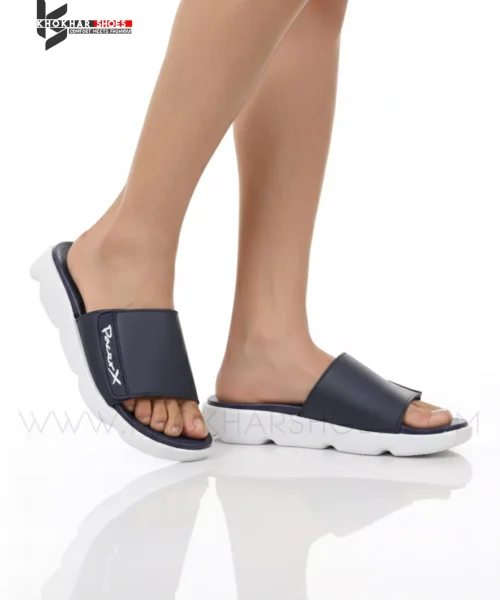 A man's feet in a pair of comfortable, navy blue and white, single-strap slides on a white background.